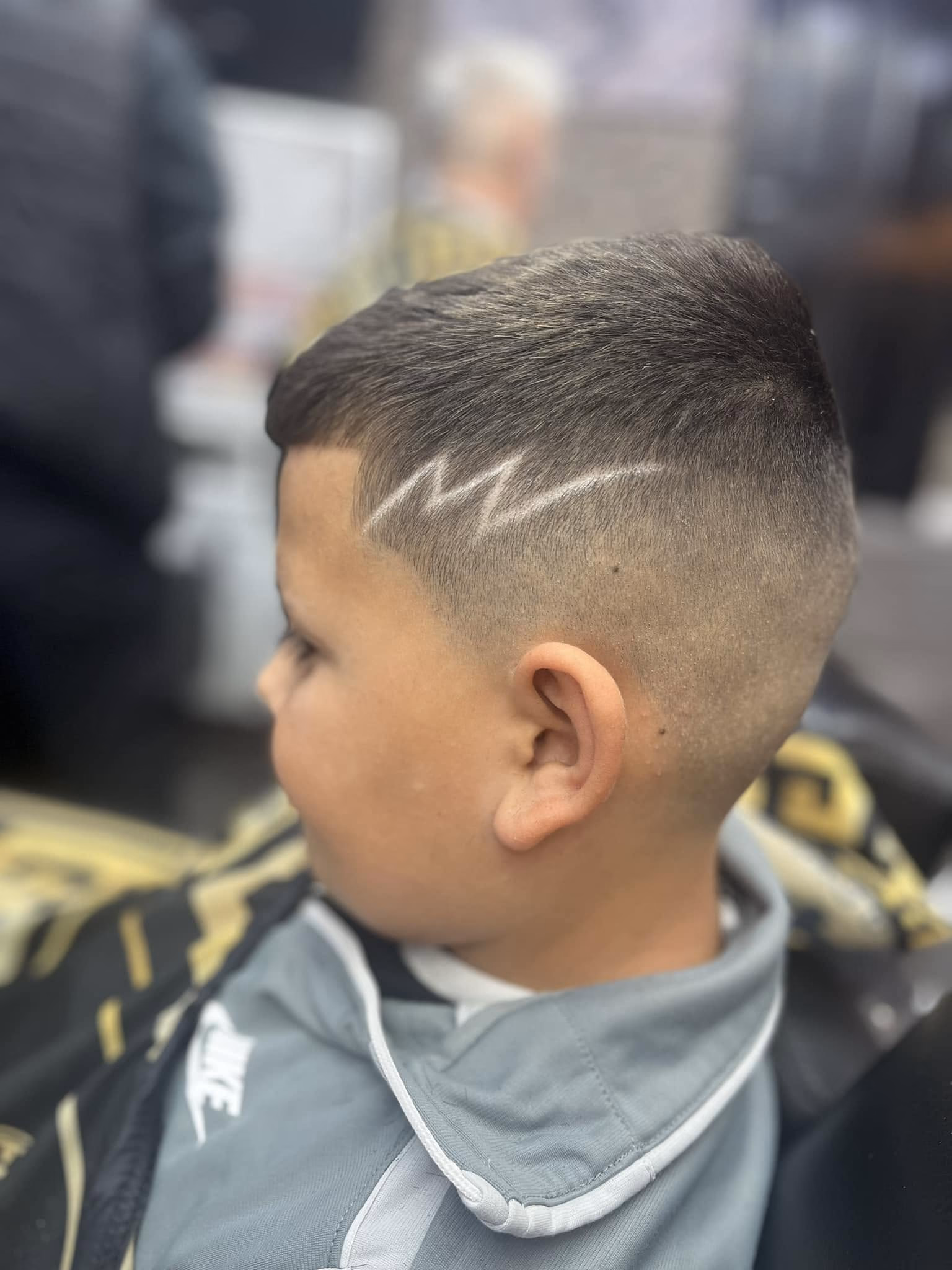 High skin fade with a lightning bolt shaved into the side and a short combed top, side profile